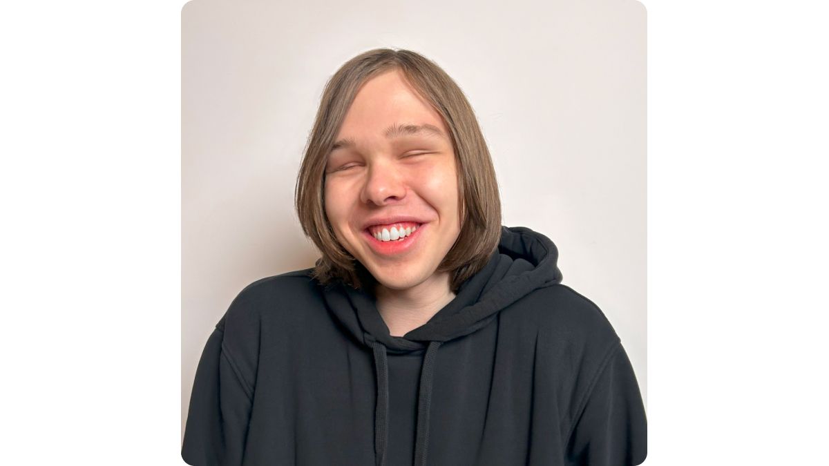 На фото — портрет Тимофея Горшкова, студента МГУ, инклюзивного волонтера и музыканта. Он широко улыбается.